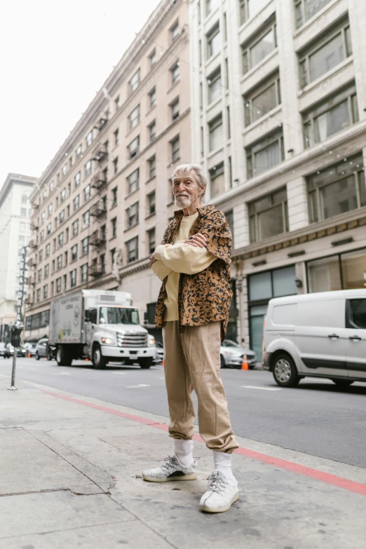 a man standing on the side of a street, by Nina Hamnett, unsplash, renaissance, jay leno with gray skin, grizzled, streetwear, wearing pajamas