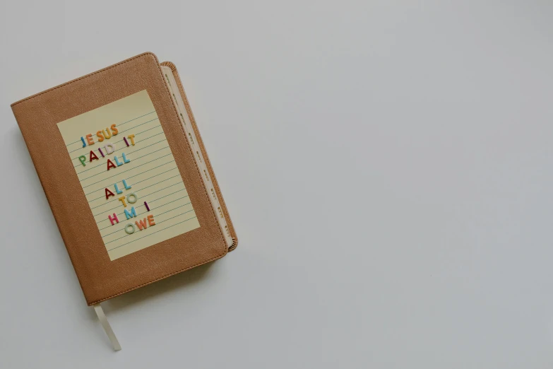 a book sitting on top of a white table, letters, product image, brown, multi - coloured