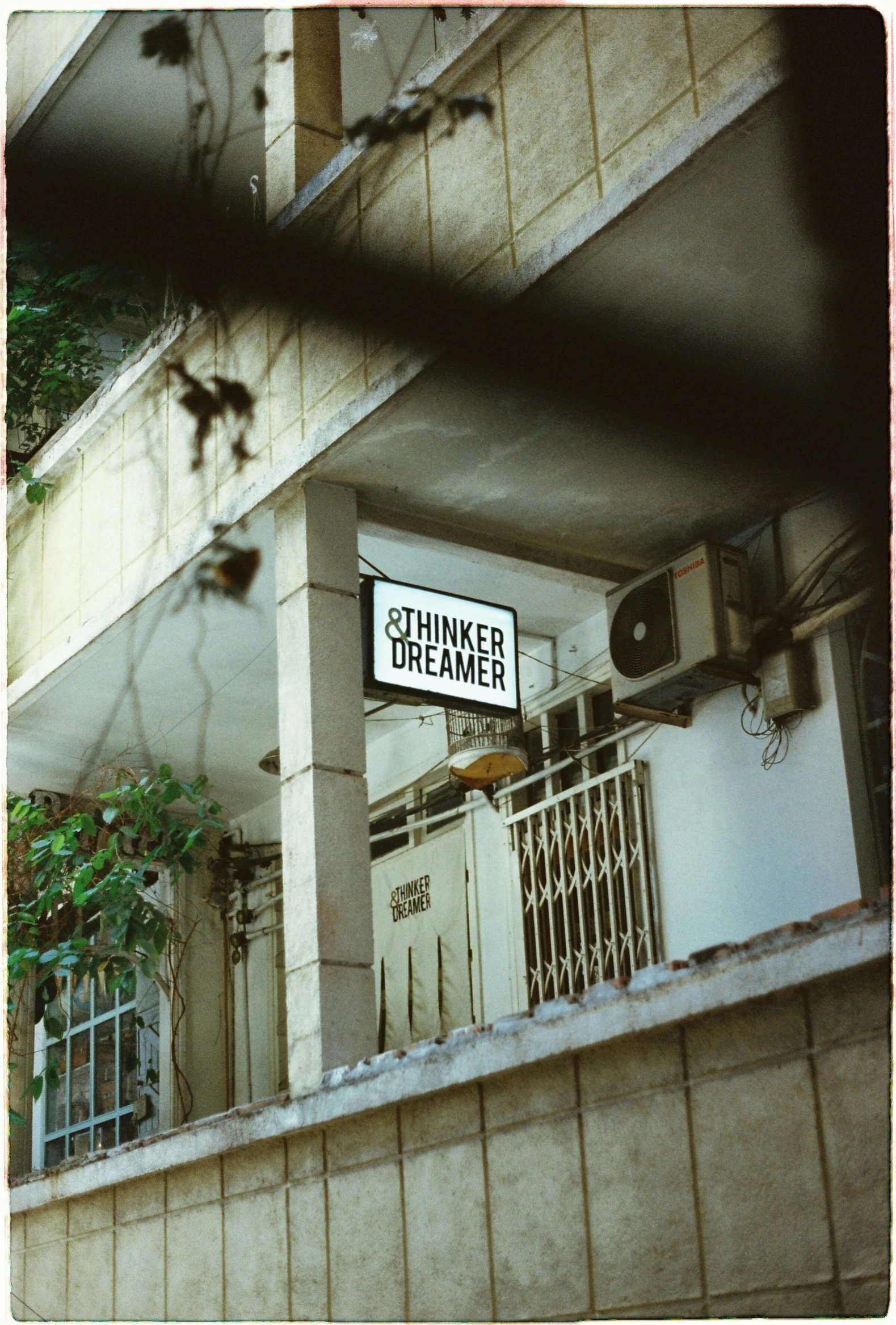 a white street sign sitting on the side of a building, inspired by Nan Goldin, you may say i'm a dreamer, 1970s philippines, 1999 photograph, dreamy chinese town