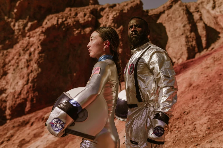 a man and a woman in space suits standing next to each other, pexels contest winner, afrofuturism, official vuitton editorial, lunar soil, film still promotional image, bo bartlett