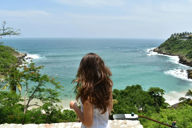 a woman sitting on a ledge looking at the ocean, a picture, avatar image, bali, sea - green and white clothes, instagram photo