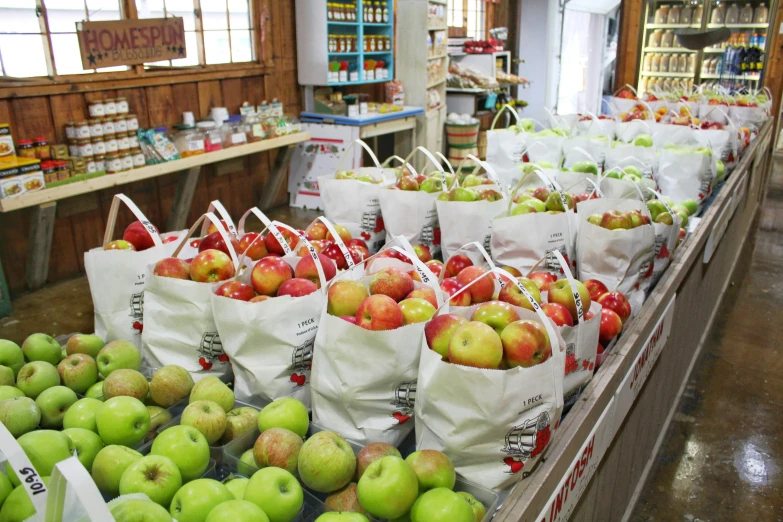 a store filled with lots of green and red apples, bags on ground, cream of the crop, thumbnail, no cropping