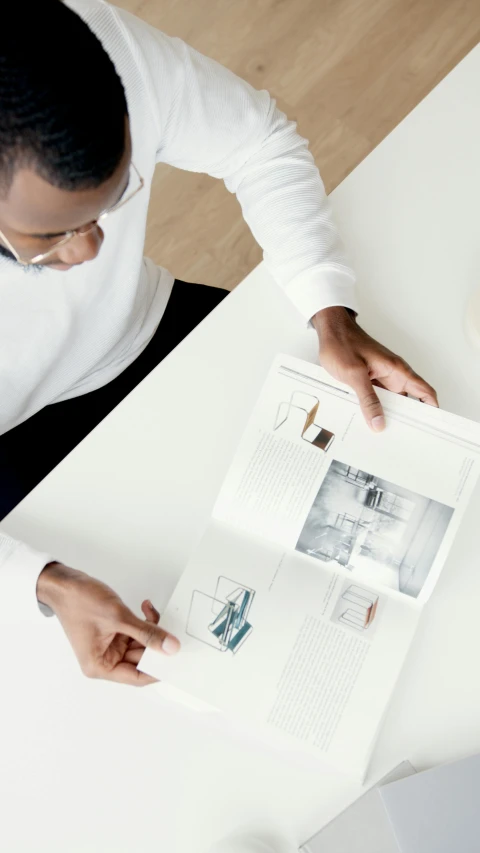 a man sitting at a table reading a magazine, pexels contest winner, architect studio, white color scheme, inspect in inventory image, - 9