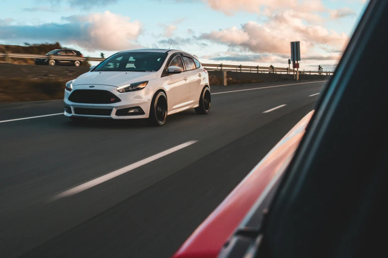 a white car driving down a highway next to a red car, pexels contest winner, ford, focus stacked, magic hour, front