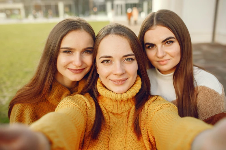 three young women taking a selfie in a park, trending on pexels, yellow, wearing turtleneck, center parted brown hair, photoshoot for skincare brand