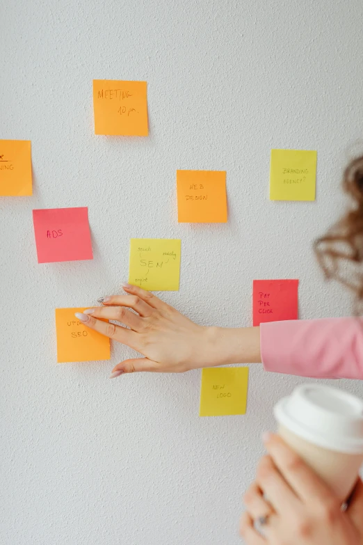 a woman standing in front of a wall covered in post it notes, product view, small features, square, multicoloured