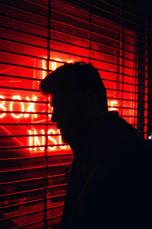 a man standing in front of a red neon sign, inspired by Nan Goldin, pexels contest winner, profile image, silhouette of a man, hiding, bad boy