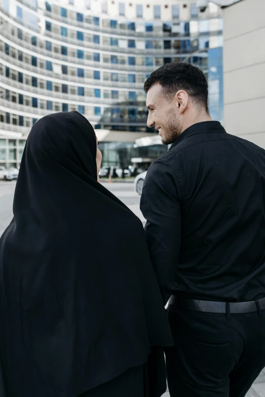 a man in a black shirt and a woman in a black hijab, pexels contest winner, symbolism, security, ( ( theatrical ) ), his back is turned, coworkers
