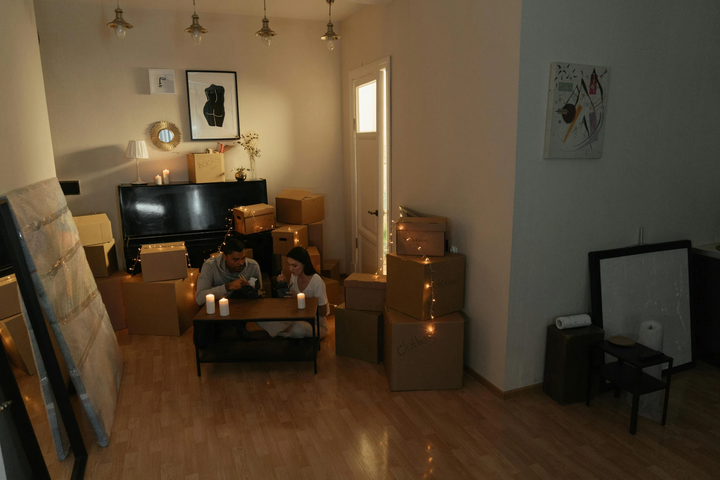 a couple of people sitting on a couch in a living room, in a room full of candles, cardboard, profile image, small room