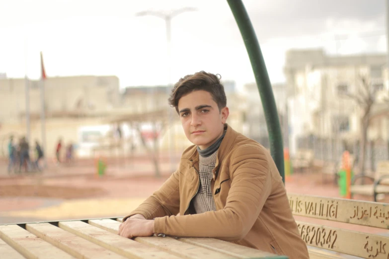 a man sitting on top of a wooden bench, ahmad merheb, young face, low quality photograph, multi - coloured