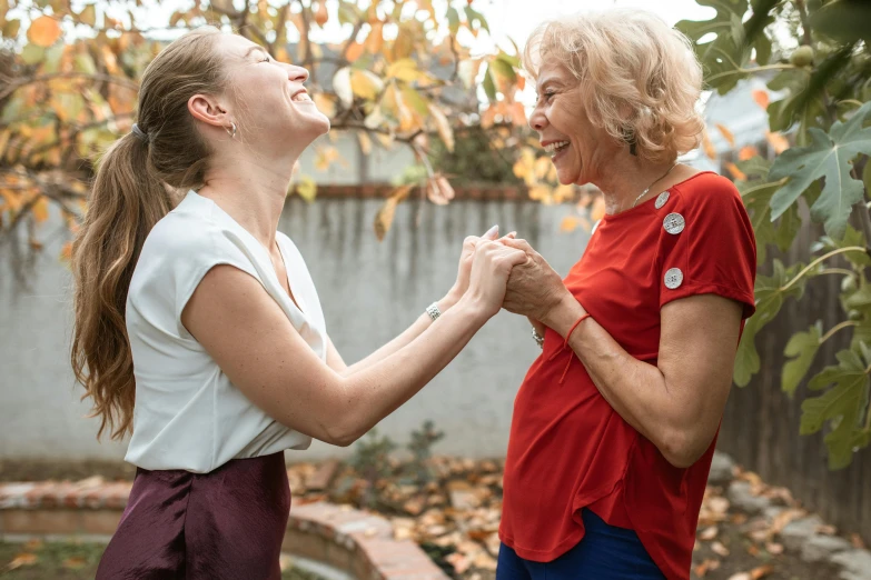 a couple of women standing next to each other, pexels contest winner, happening, smiling and dancing, old and young, holding each other hands, straya