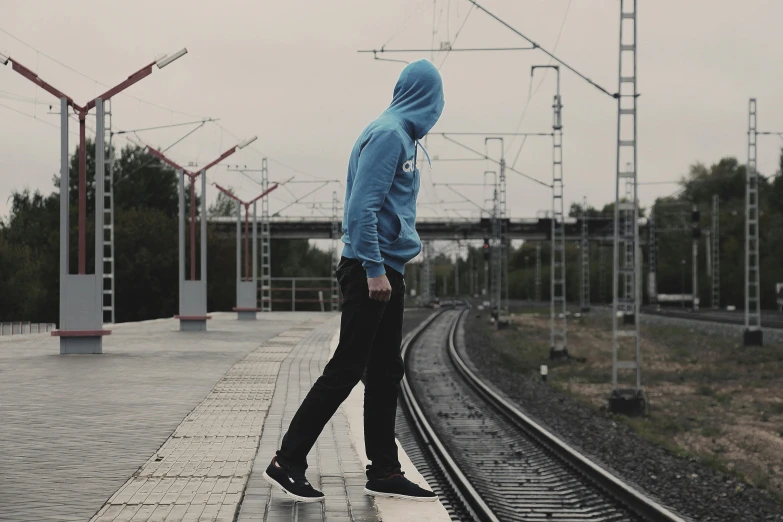 a man in a blue hoodie standing on a train track, pexels contest winner, full body profile pose, outlive streetwear collection, profile picture 1024px, depressing atmosphere