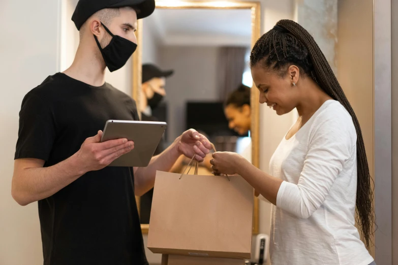 a man and a woman are looking at a tablet, by Everett Warner, pexels contest winner, renaissance, getting groceries, white man with black fabric mask, delivering parsel box, sydney hanson