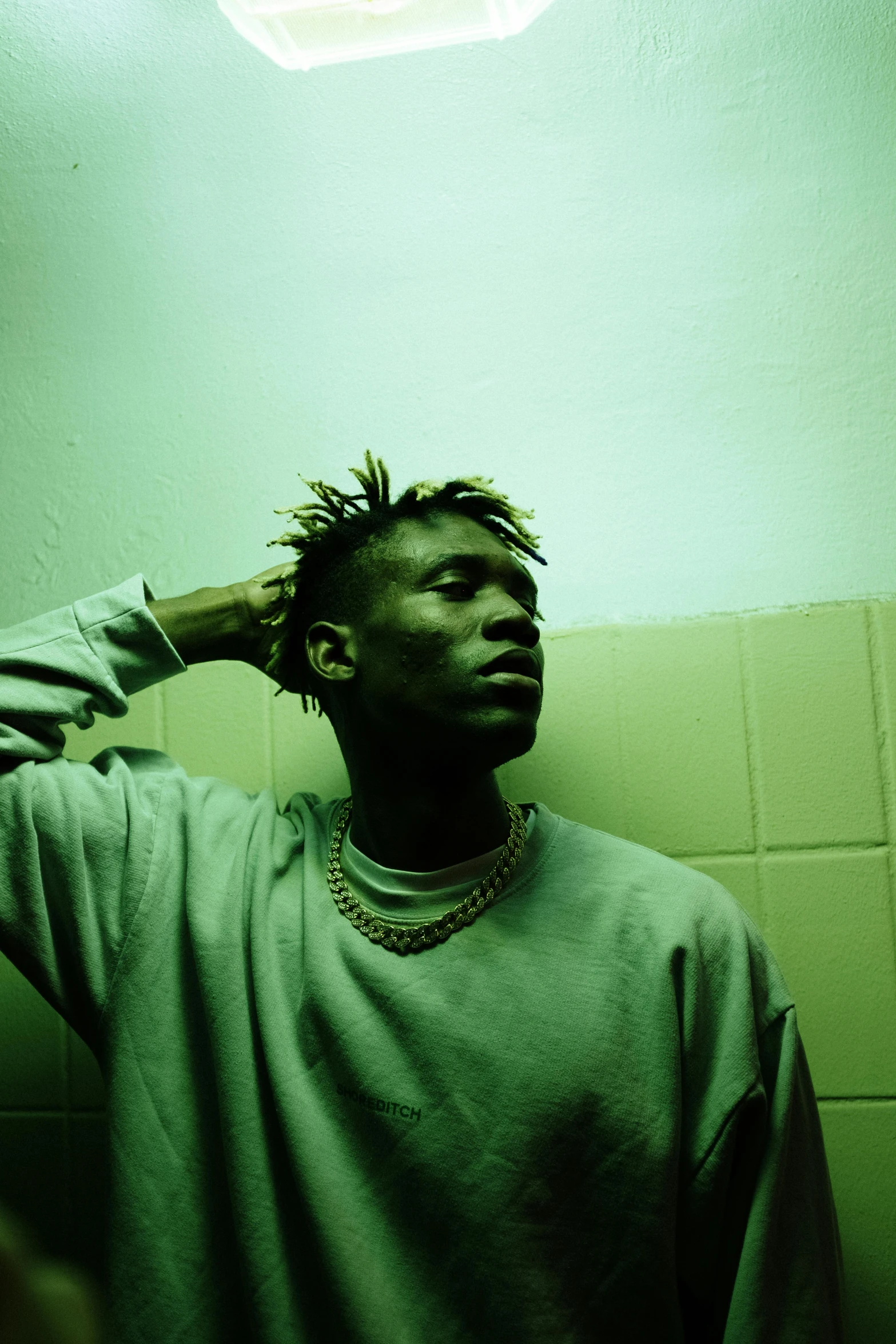 a man standing in front of a mirror in a bathroom, an album cover, inspired by Barthélemy Menn, trending on pexels, realism, green hair, brown skinned, (night), thoughtful pose