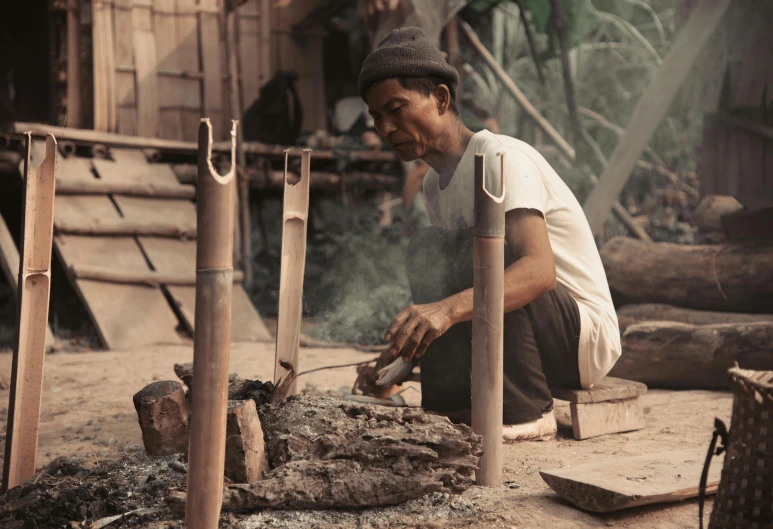 a man that is sitting in front of a fire, a colorized photo, pexels contest winner, sumatraism, carpenter, made of bamboo, 1960s color photograph, made of tar