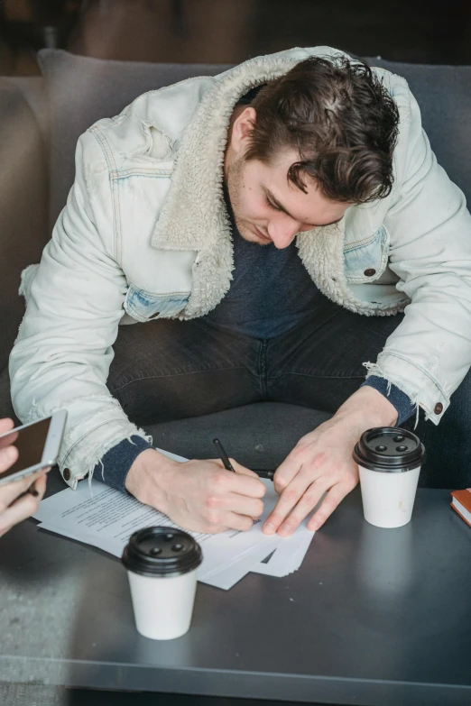 a man sitting at a table writing on a piece of paper, aussie baristas, hozier, lgbtq, ignant