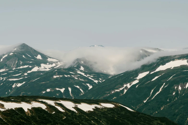 a man flying a kite on top of a snow covered mountain, by Andrei Kolkoutine, trending on unsplash, hurufiyya, low clouds after rain, 000 — википедия, seen from afar, taiga landscape