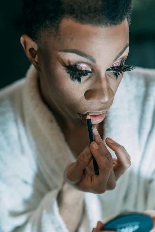 a woman in a bathrobe applying her makeup, an album cover, inspired by Lily Delissa Joseph, trending on pexels, ru paul\'s drag race, smoothed lip line, black makeup, shot with sony alpha 1 camera