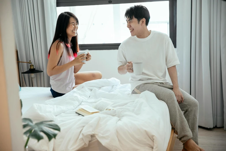 a man and a woman sitting on a bed, by Jang Seung-eop, pexels contest winner, teenager hangout spot, with a white mug, both laughing, listing image