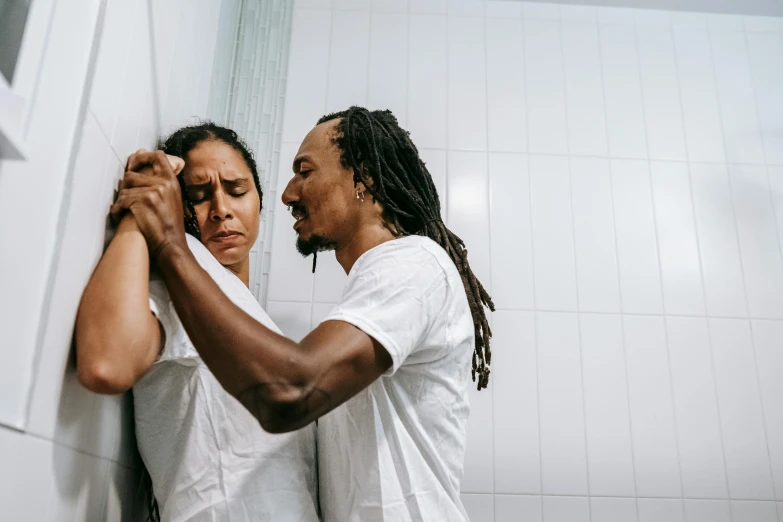 a man standing next to a woman in a bathroom, by Julia Pishtar, pexels contest winner, dreadlock breed hair, crying and reaching with her arm, fighting each other, kara walker