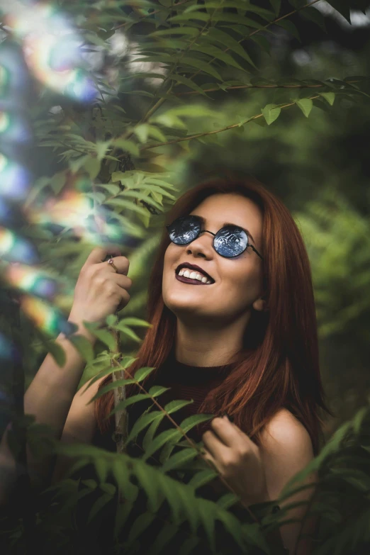 a woman that is standing in the grass, pexels contest winner, wearing round glasses, ( redhead, happy trippy mood, lush foliage