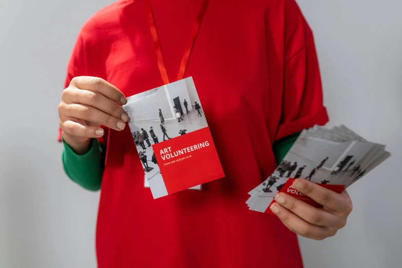 a person in a red shirt holding some cards, an album cover, by Dan Content, trending on unsplash, red ribbon, brochure, courtesy of centre pompidou, close up front view