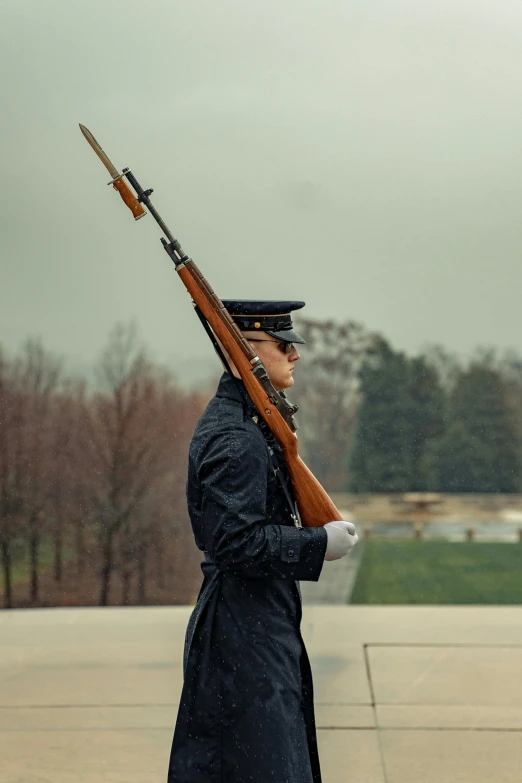 a man in a military uniform holding a rifle, a colorized photo, by Carey Morris, visual art, slight overcast weather, inauguration, facing away, rifle