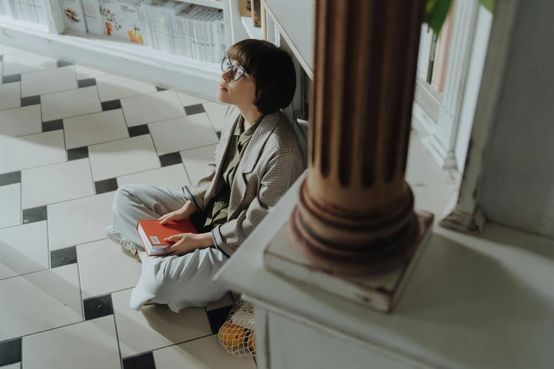 a woman sitting on the floor reading a book, pexels contest winner, hyperrealism, wearing square glasses, profile image, low angle photo, androgynous person