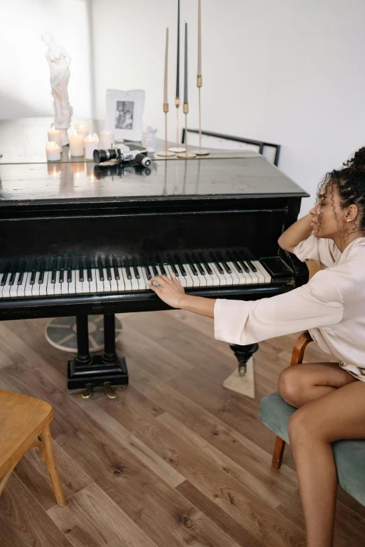 a woman sitting on a chair in front of a piano, trending on pexels, ashteroth, on a white table, romance, embarrassing