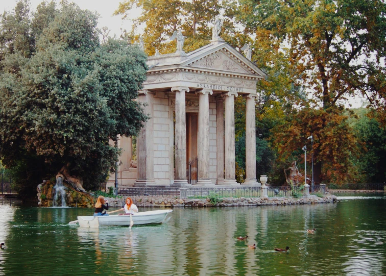 a couple of people in a small boat on a lake, flickr, neoclassicism, water temple, 1999 photograph, gardens and fountains, greek-esque columns and ruins