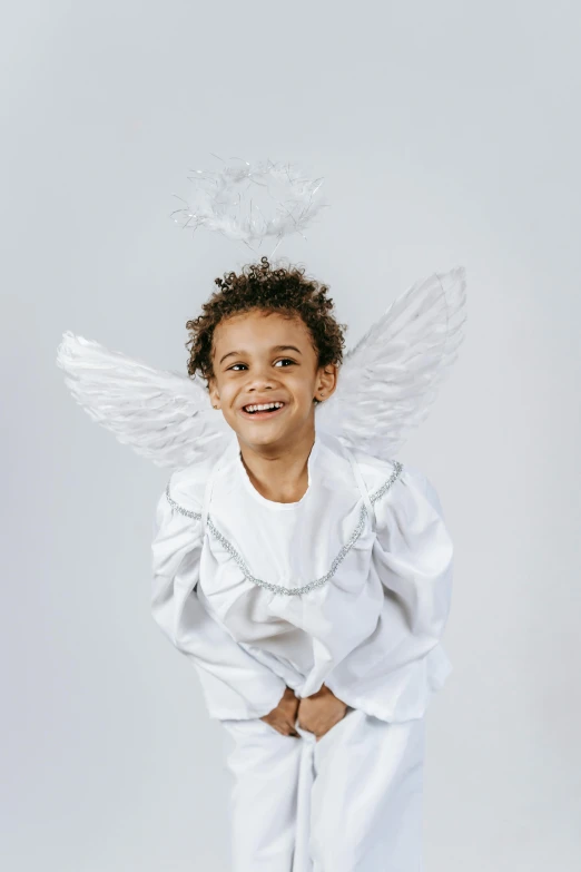 a little boy dressed up as an angel, pexels contest winner, plain background, looking happy, white and silver, wearing festive clothing