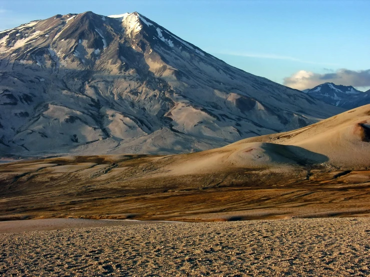 a man riding a snowboard on top of a snow covered mountain, by Andrei Kolkoutine, trending on unsplash, hurufiyya, infographic of active volcanoes, deserted sand, seen from afar, gravel and scree ground