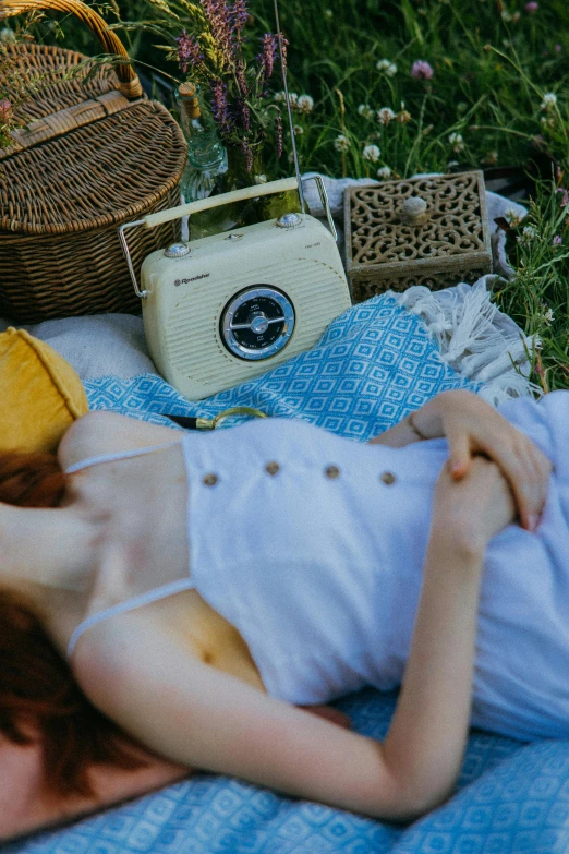 a woman laying on a blanket in the grass, an album cover, inspired by Konstantin Somov, pexels contest winner, radios, detail shot, a handsome, vintage inspired
