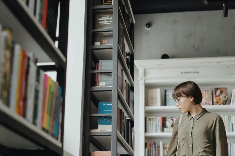 a woman standing in front of a bookshelf in a library, pexels contest winner, side view future coder man, young boy, ignant, walking to the right