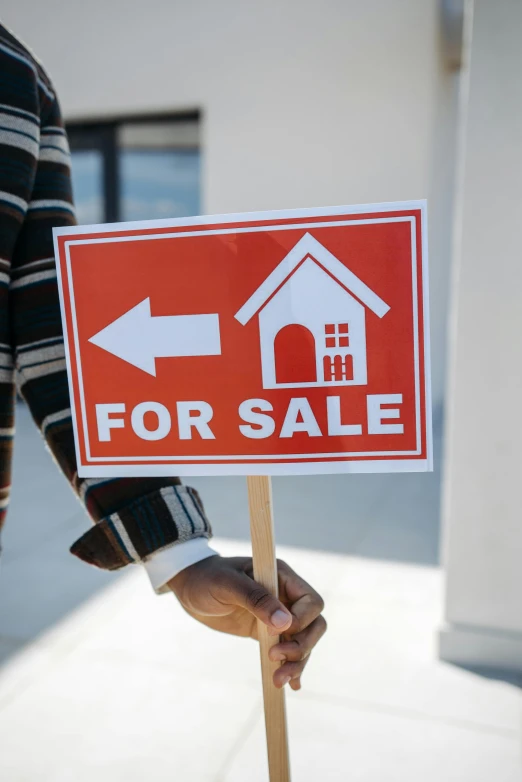 a man holding a for sale sign in front of a house, a photo, trending on unsplash, modernism, square, diverse, ( ( photograph ) ), holding a crowbar