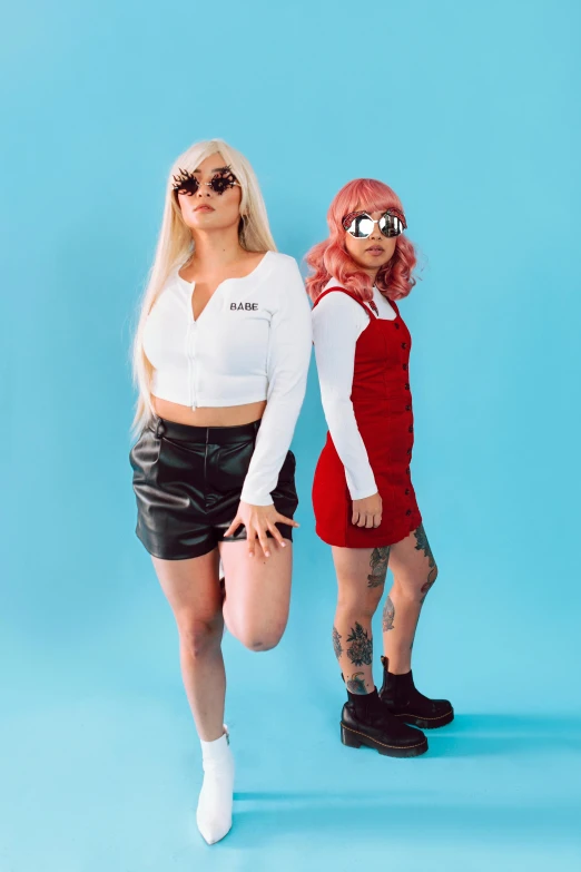 two women standing next to each other on a blue background, an album cover, trending on pexels, realism, wearing red tainted glasses, wearing overalls, platinum blonde, wearing crop top and miniskirt