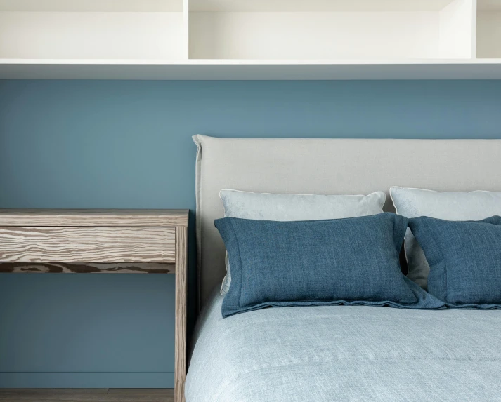 a bed room with a neatly made bed and blue walls, inspired by Bedwyr Williams, shelves, close up details, thumbnail, high detail photo