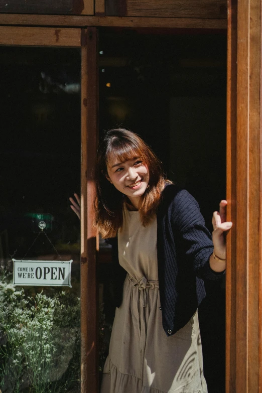 a woman standing in the open door of a building, coffee shop, welcoming grin, 奈良美智, profile image