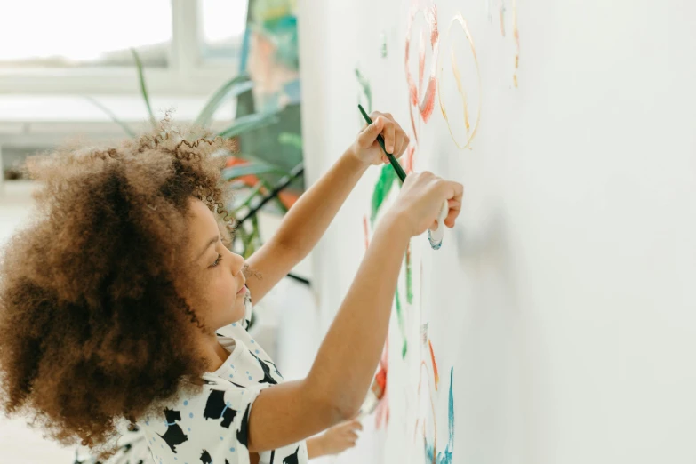 a little girl that is writing on a wall, a child's drawing, by Olivia Peguero, pexels contest winner, interactive art, painting on a badge, whiteboards, light skinned african young girl, model painting