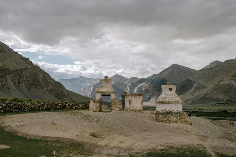 a couple of stone pillars sitting on top of a dirt field, unsplash contest winner, himalayas, background image, small buildings, 000 — википедия