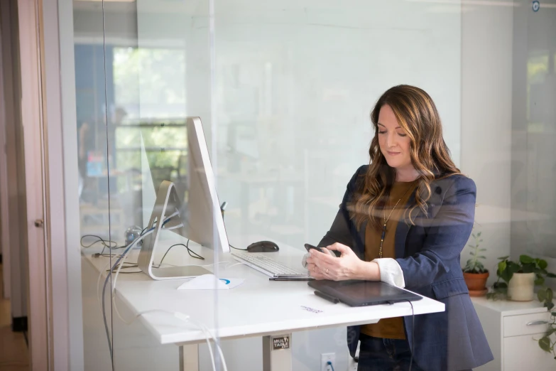 a woman sitting at a desk in front of a computer, by Jessie Algie, unsplash, standing, lachlan bailey, in an office, digital oth