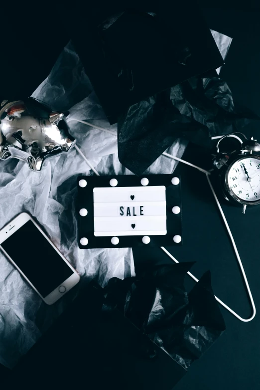 a pile of clothes sitting on top of a table next to a clock, a black and white photo, trending on pexels, neon electronic signs, smartphone photo, sales, dark themed