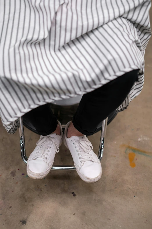 a person that is sitting in a chair, by Emily Shanks, wearing white sneakers, stripey pants, white hijab, dynamic closeup