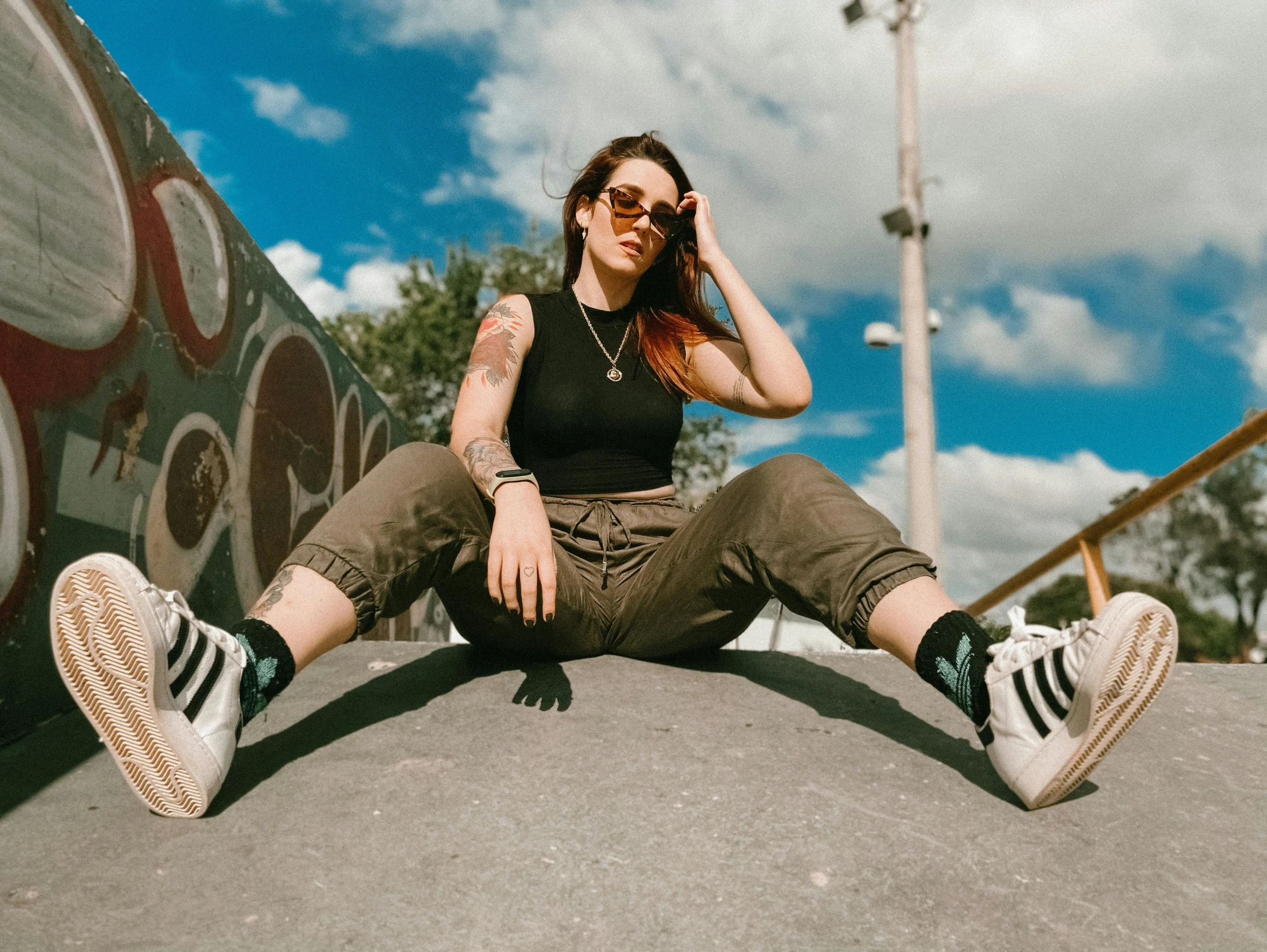 a woman sitting on the ground talking on a cell phone, inspired by Elsa Bleda, trending on pexels, graffiti, wearing cool sunglasses, looking up at camera, irish youtuber, doing a majestic pose