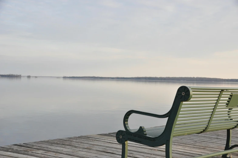 a green bench sitting on top of a wooden dock, by Winona Nelson, pexels contest winner, grey, calm evening, sitting on bench, gazing off into the horizon