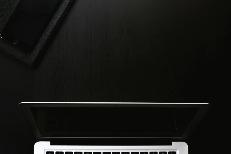 a laptop computer sitting on top of a wooden desk, by Carey Morris, minimalism, black on black, iphone wallpaper, lacquered, blank