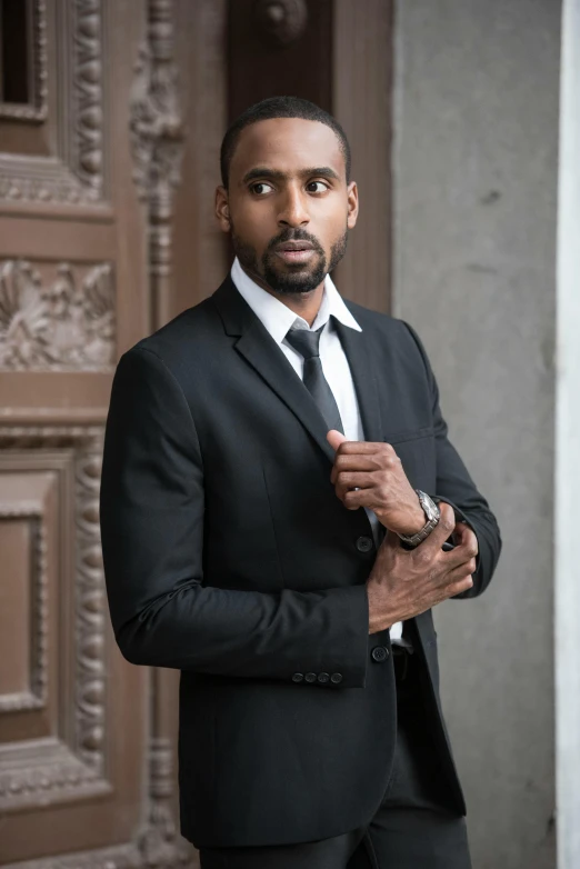 a man in a suit and tie standing in front of a door, inspired by Rajmund Kanelba, pexels contest winner, renaissance, somali attire, wearing causal black suits, model shoot, indian