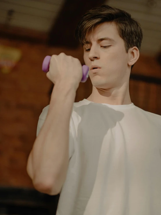a young man holding a pair of purple dumbbells, by Robbie Trevino, declan mckenna, gif, high quality image