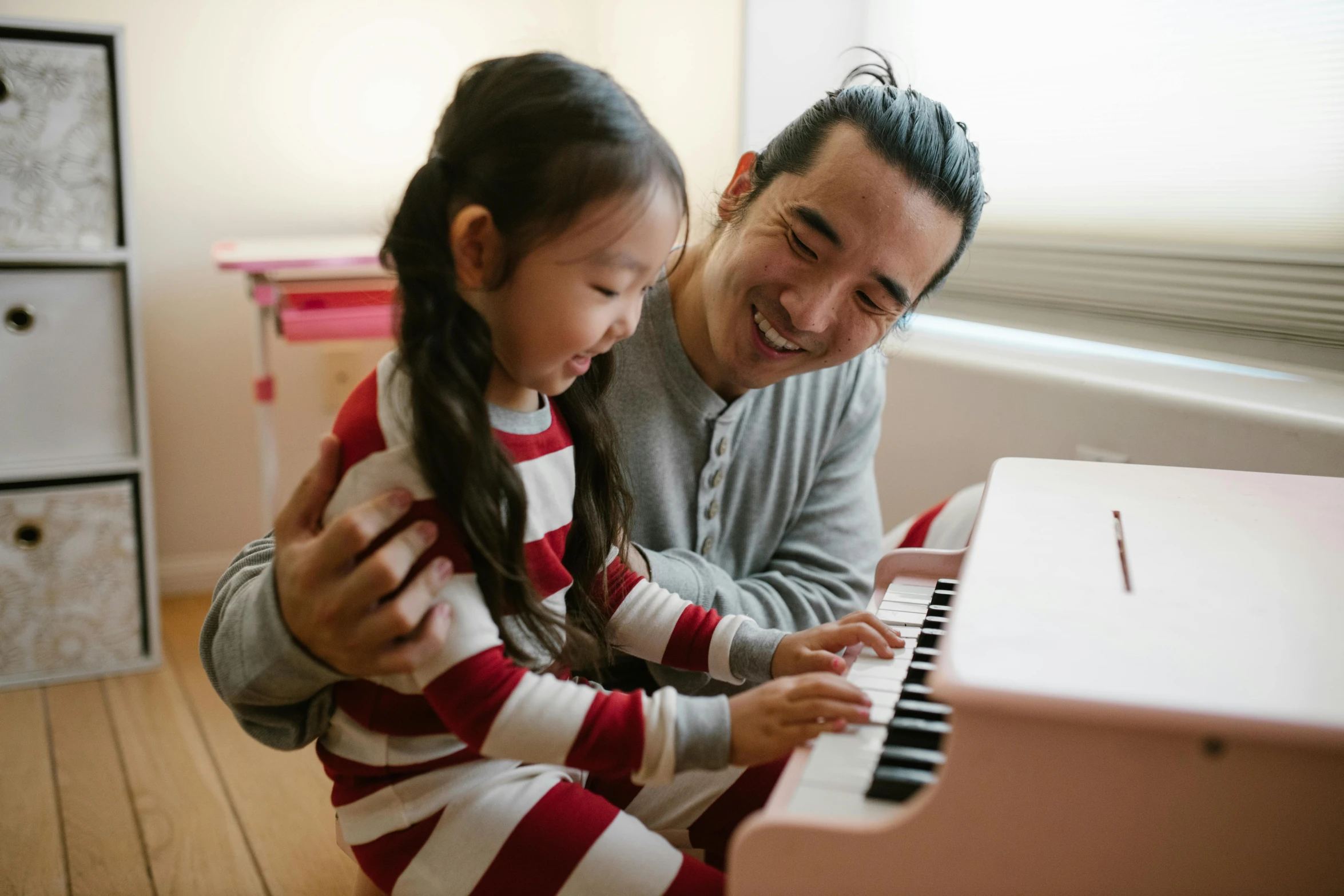 a man sitting next to a little girl playing a piano, pexels contest winner, avatar image, asian descent, teacher, smiling playfully