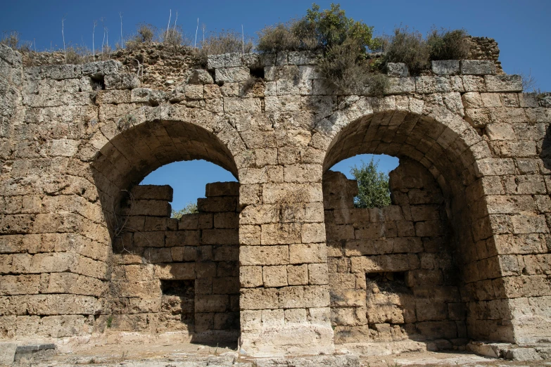 an old stone building with two arched windows, by Tom Wänerstrand, pexels contest winner, romanesque, aqueducts, cyprus, wall of water either side, photo from the dig site